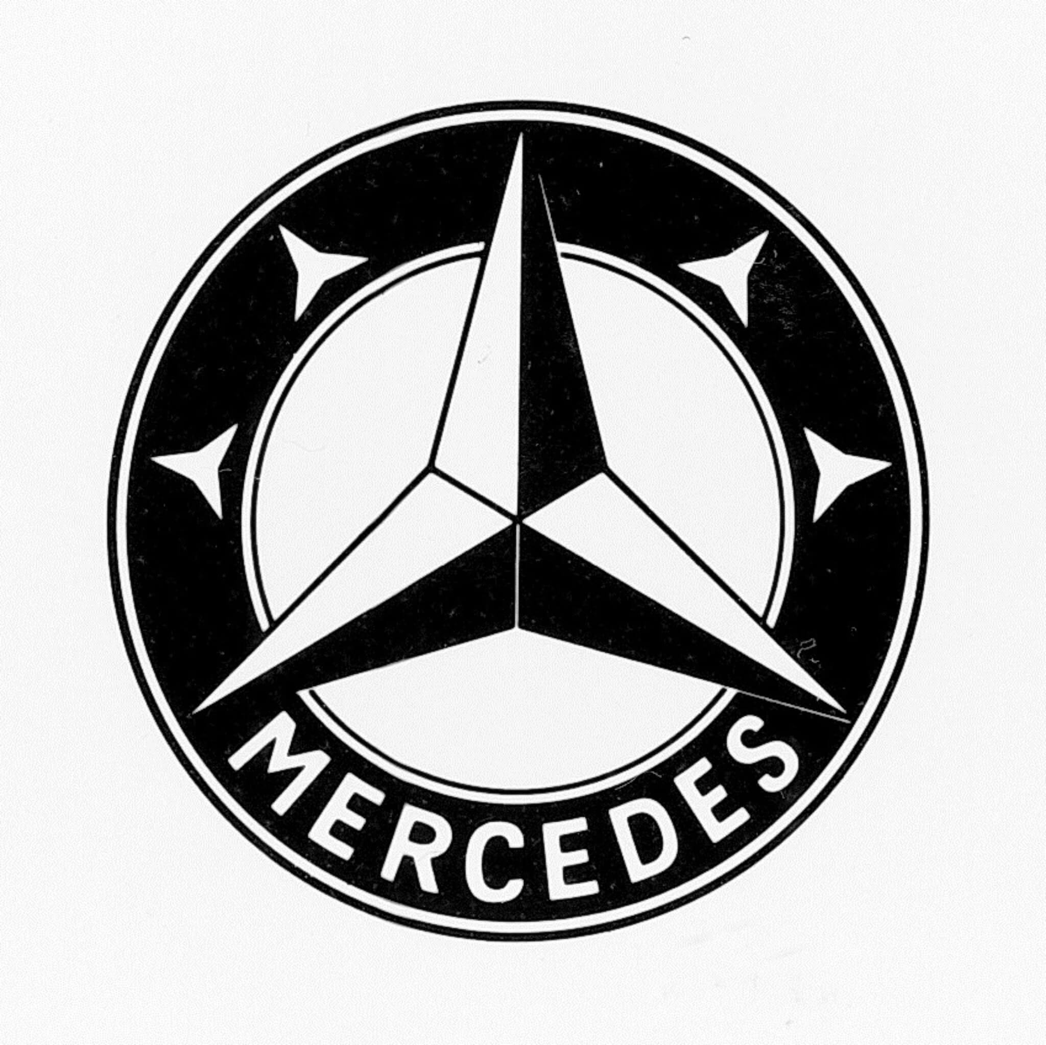 Estrela de três pontas, dentro de um anel, com quatro estrelas mais pequenas dentre deste, duas de cada lado. E ainda a inscrição Mercedes no anel
