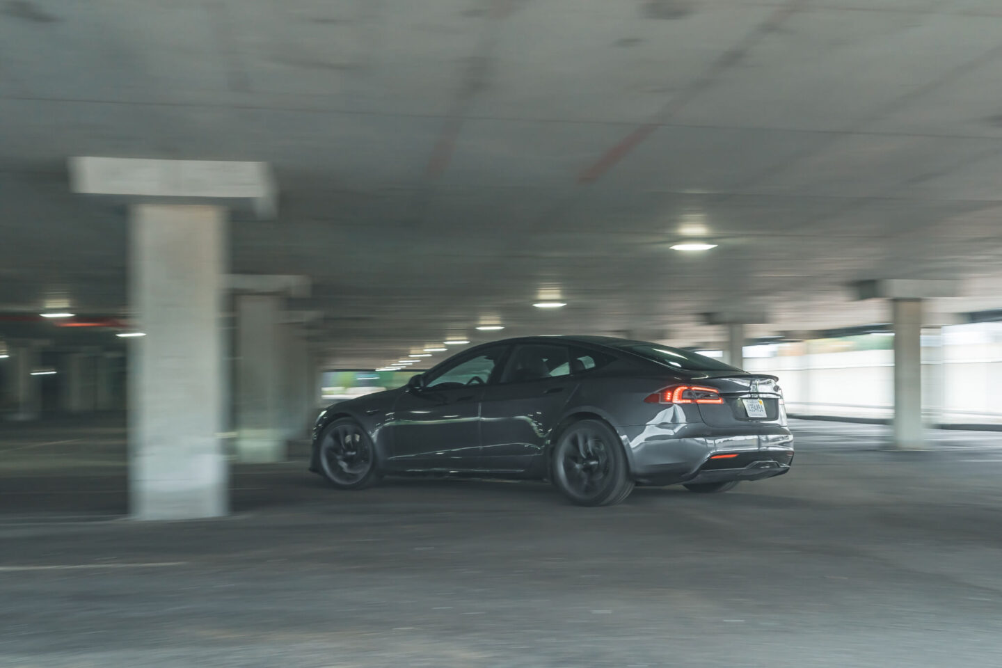 Tesla model s plaid em parque subterrâneo, vista 3/4 traseira