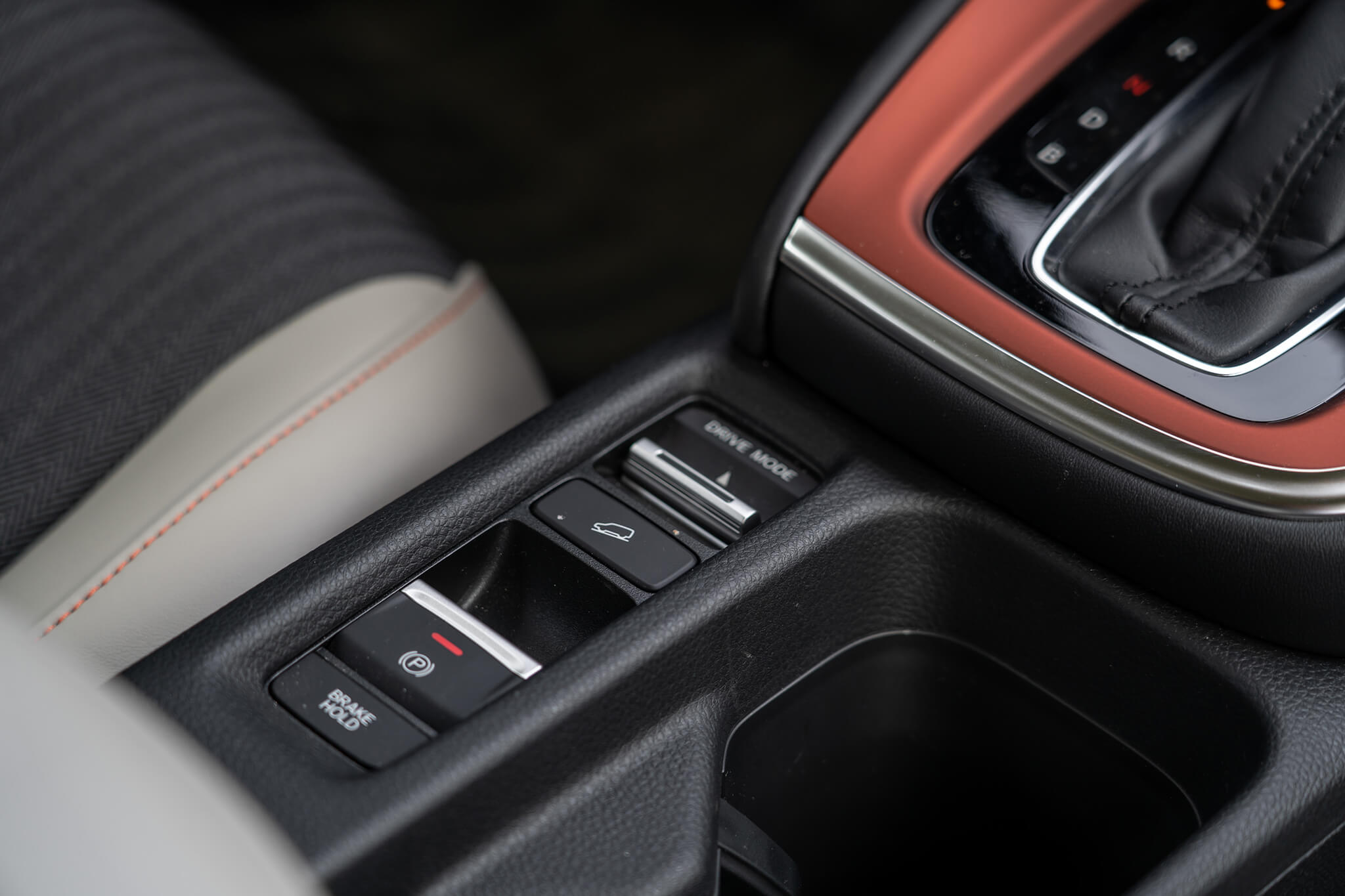 Detalhe da consola central que mostra travão de mão eletrónico, controlo de descidas e botão para mudar modos de condução.