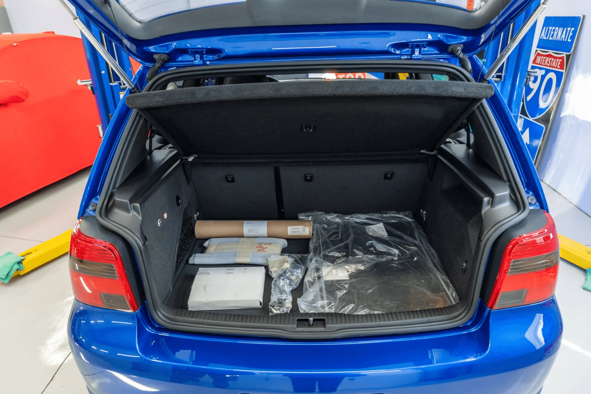 Bagageira com tapetes dentro do plástico e documentos do carro