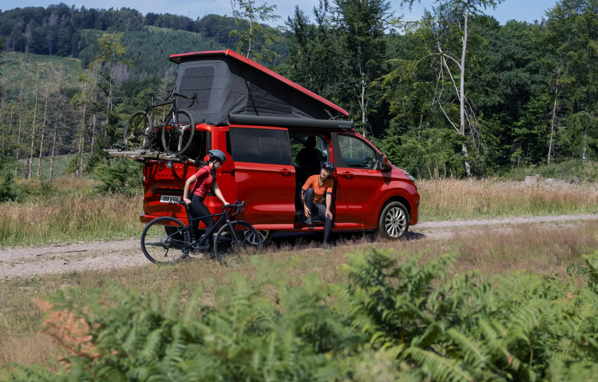 Ford Transit Custom Nugget, com teto basculante e porta traseira abertos e bicicleta instalada em suporte traseiro