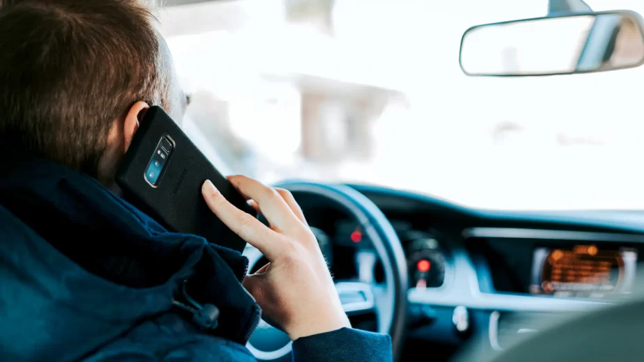 Pessoa ao volante de um carro e a falar ao telefone