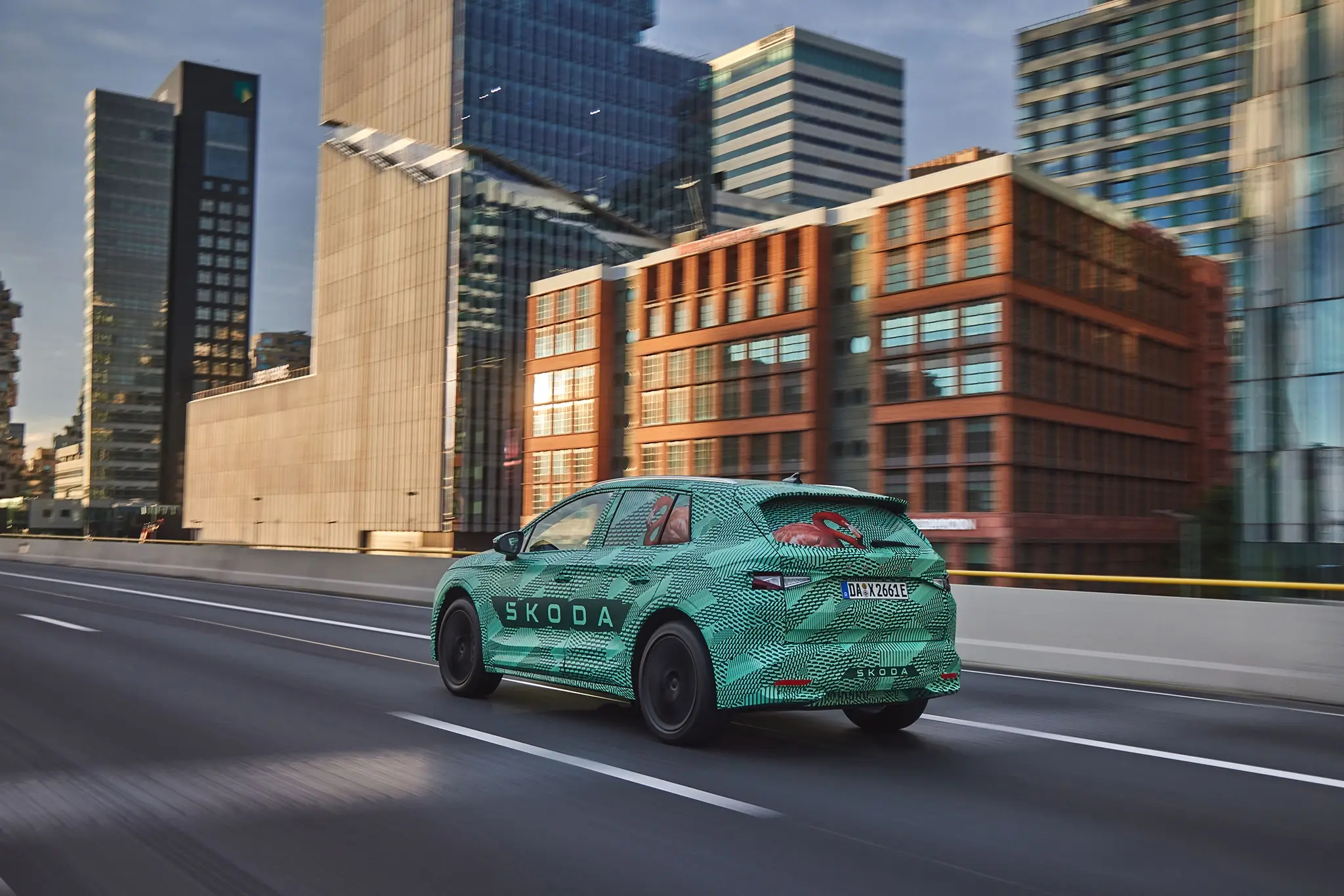 Skoda Elroq camuflado - 3/4 de traseira com prédios de fundo